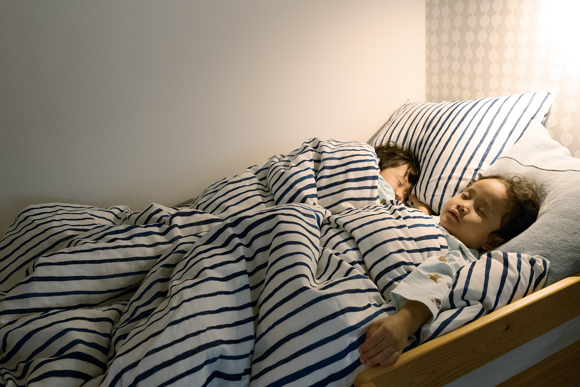 紺と白のストライプ寝具でぐっすり眠る子ども